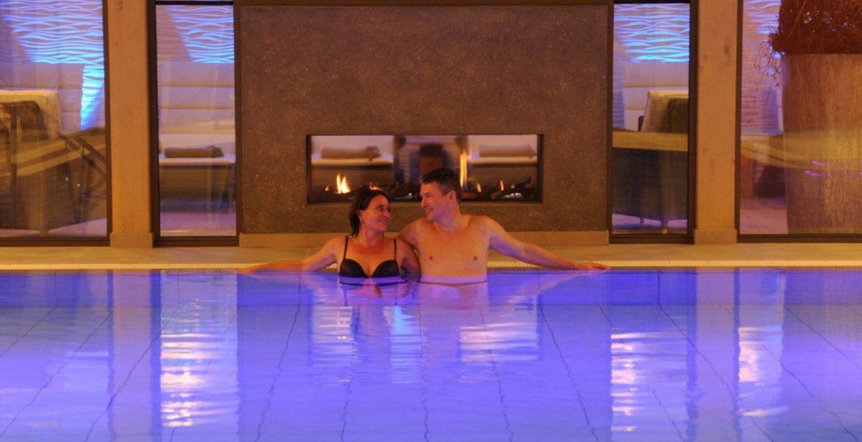 Hotelschwimmbad Innenpool blau beleuchtet mit Pärchen