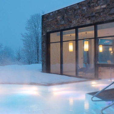 Hotelschwimmbad Außenpool mit Unterwasserbeleuchtung und verschneiter Terrasse