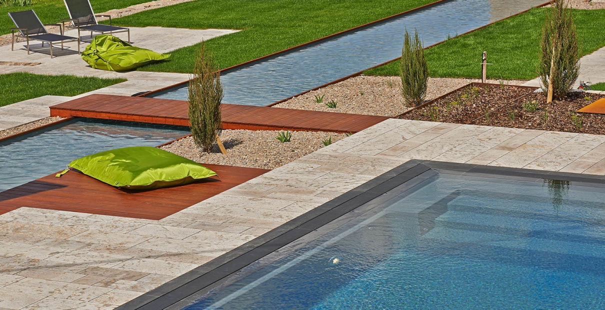 Außenpool mit Wasserzulauf und Terrasse aus Holz und Stein