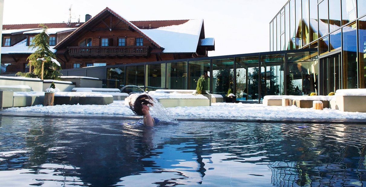 Hotelschwimmbad Außenpool im Winter mit badender Frau