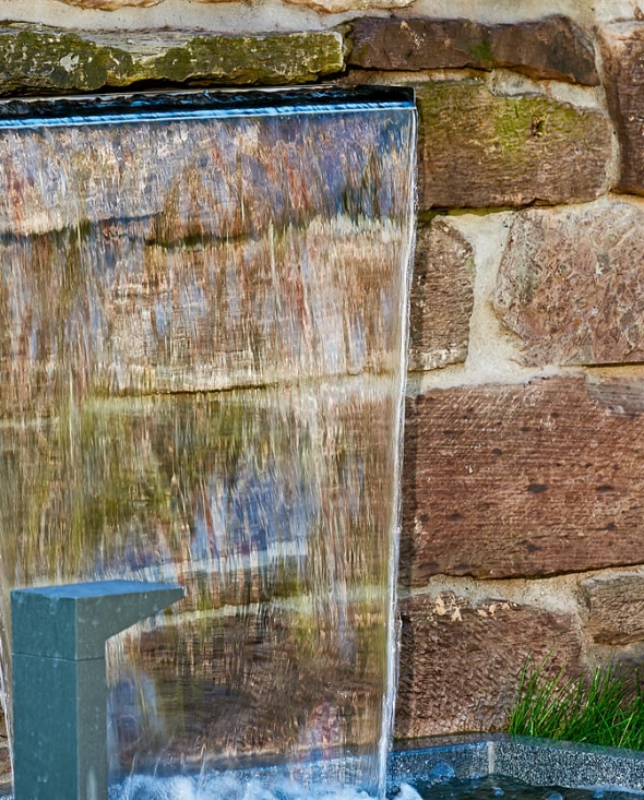 Außenpool mit Wasserfall vor Rustikaler Steinwand