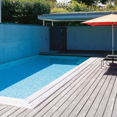 Sonnenplateau Außenpool Holzterrasse und Sichtbetonwand