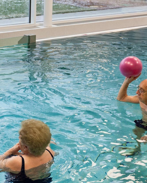 Klinikbad mit Senioren, die Wasserball spielen