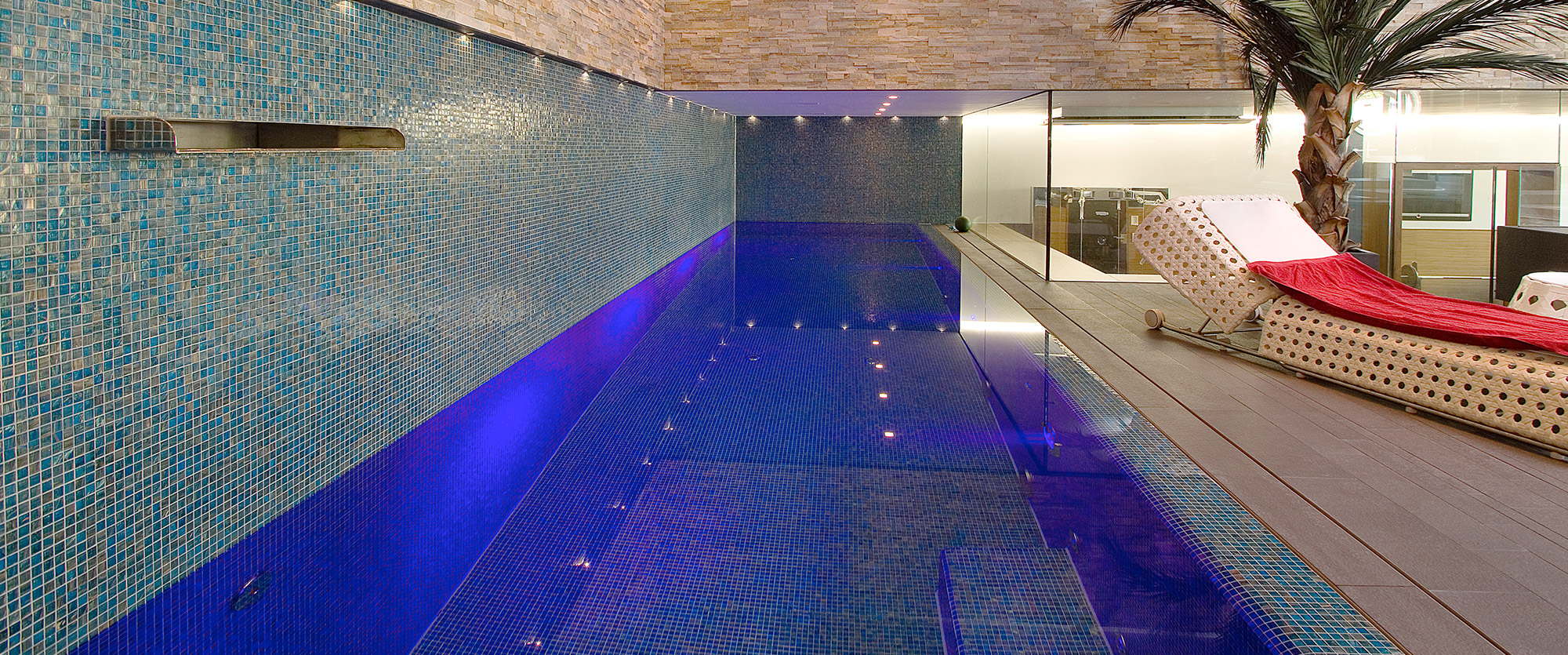 Indoor pool illuminated blue with relaxation lounger