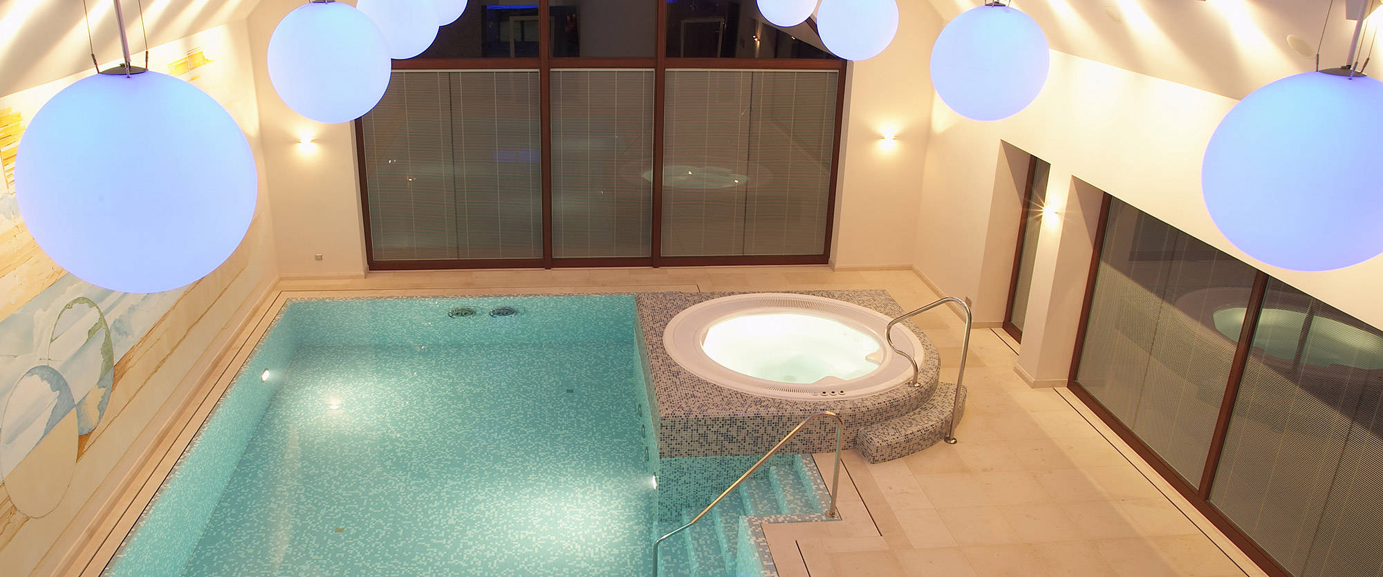 Indoor pool with blue ceiling lighting and whirlpool